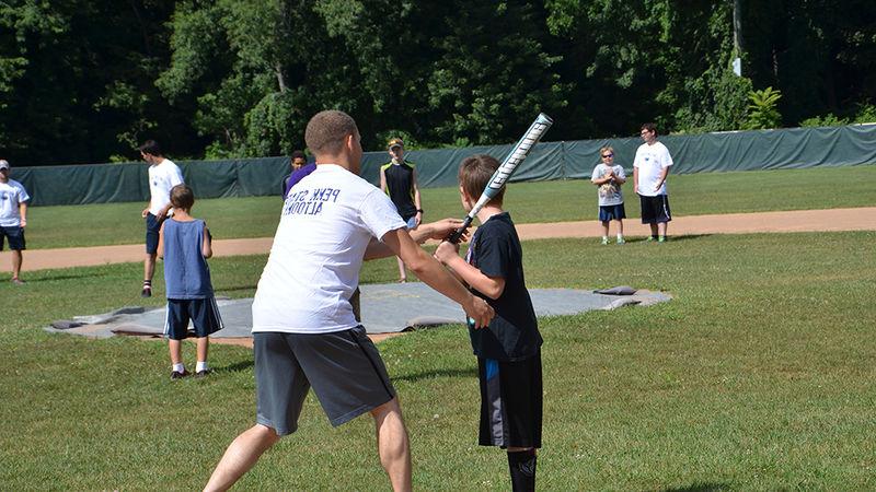 Students assist children in a game of baseball as part of the Voluntoona community service effort.